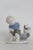This charming Porcelain Figurine is made of porcelain. This adorable piece features a young boy sitting at a pot with a...
