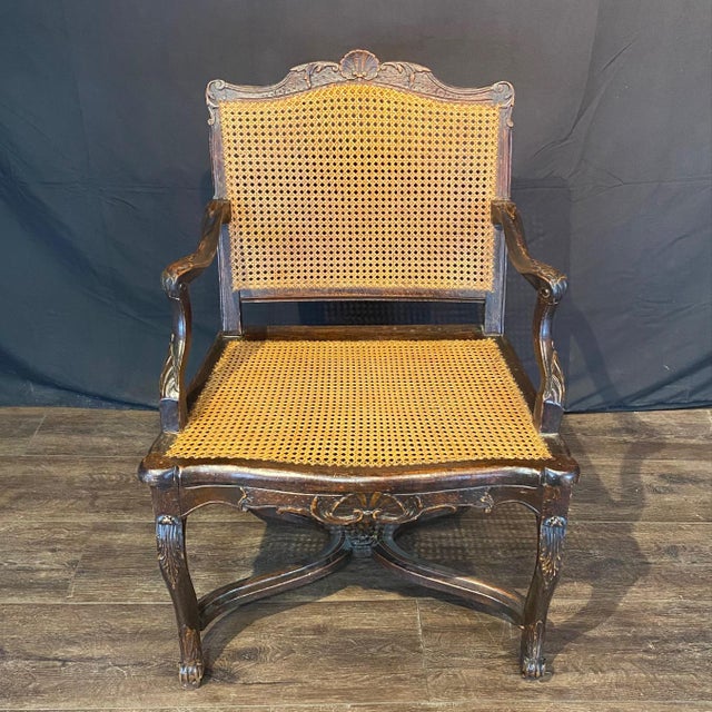 Elegant French 19th century caned oak armchairs, featuring finely hand-woven cane backs and seats framed by richly carved...