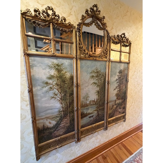Striking antique French three-panel folding screen featuring ornate giltwood frames with ribbon and floral cresting,...