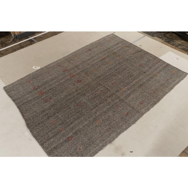 Originating between 1950-1960, a (9x10) vintage kilim rug from Turkey. Handwoven in wool, simple gray tones play with...