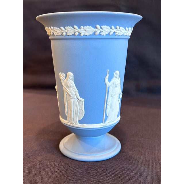 Classic Wedgwood Portland Blue Jasperware vase featuring crisp white neoclassical relief decoration. The main scene shows...