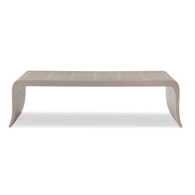 A study in form and finish, this sculptural coffee table features a continuous waterfall silhouette clad in fine faux...