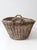 This antique wicker basket features a generous oval form, wrapped handles, and a dark wood base that gives the piece a...