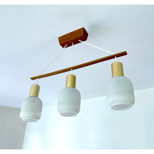 Mid Century Danish modern pendant light featuring a teak wood suspension and 3 opaline glass shades Dimensions: Height 58...