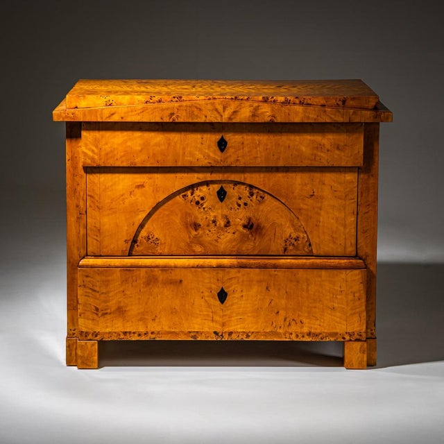 Three-drawer Biedermeier chest veneered in birch with burl veneer accents and ebonized escutcheons. The central drawer is...