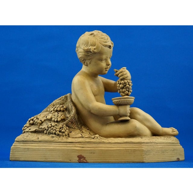 a magnificent terracotta sculpture depicting the infant bacchus with a bunch of grapes and a cup, signed "b. Rezl," dating...