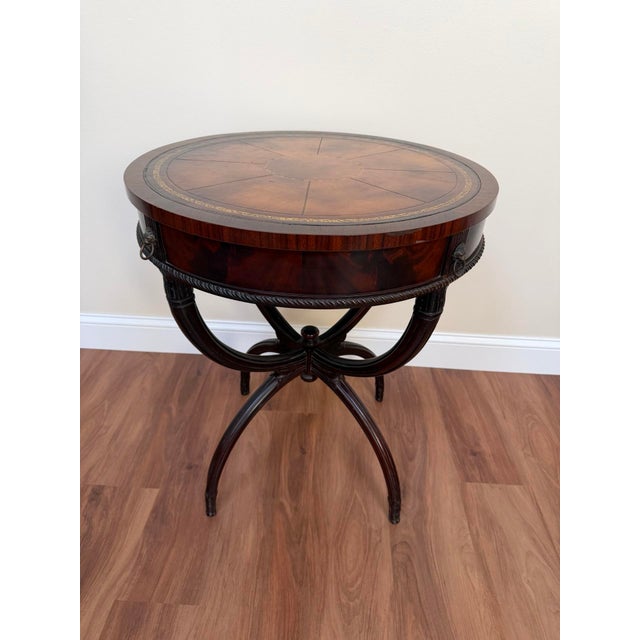 Mid-20th century Regency Revival drum table crafted in mahogany with a tooled leather inset top and classic lion-head ring...
