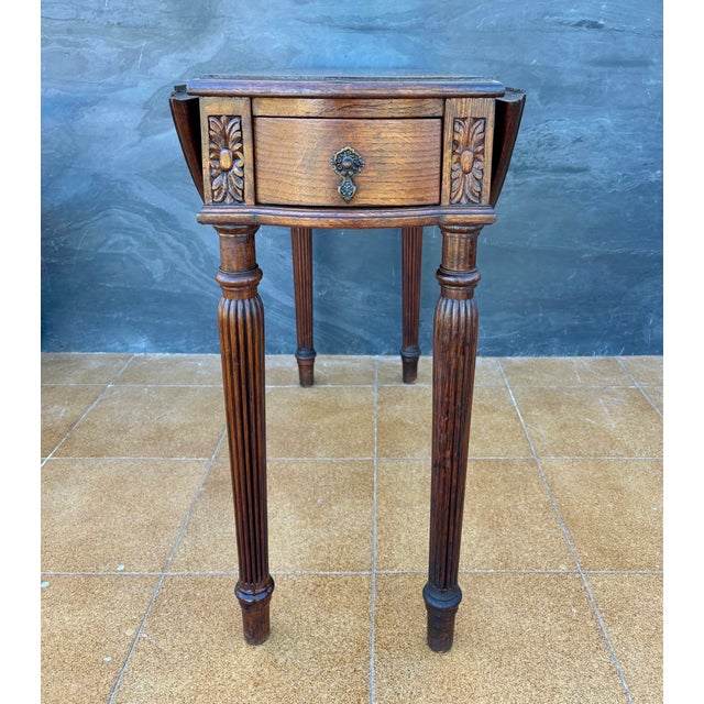 Spanish Neoclassical drop-leaf table crafted in oak, dating to the early 20th century. The table features a circular top...