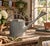 A beautifully weathered galvanized steel watering can dating to the 1960s, featuring a gracefully arched copper handle,...