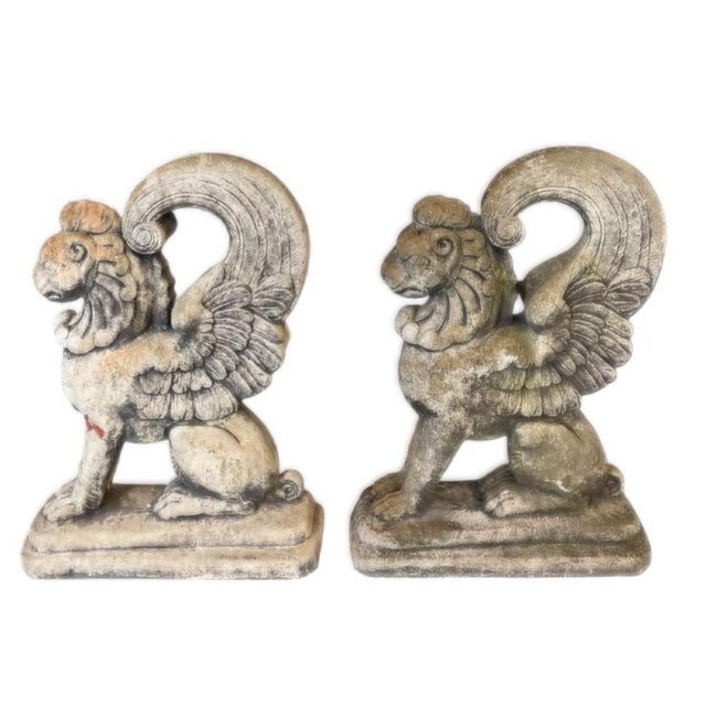 This striking pair of cast stone winged griffins (or winged lions) is sculpted in a majestic seated position, facing...