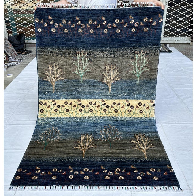 Persian Gabbeh design hand-knotted rug featuring whimsical tribal tree motifs scattered across rich horizontal bands of...