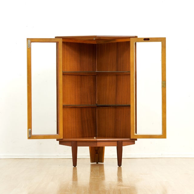This fabulous mid century corner display cabinet was manufactured by Turnidge of London during the 1950s. Produced in teak...