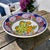 This vintage ceramic platter from Greece features hand-painted floral and fruit motifs in vibrant colors. Made by AD in...