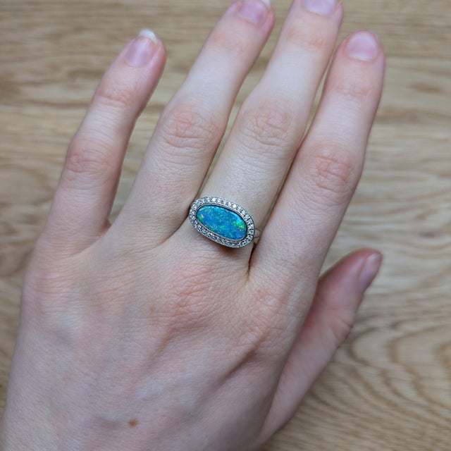 A rare boulder opal rests in a play of colour across ironstone at the centre of this solid 14K white gold ring, surrounded...