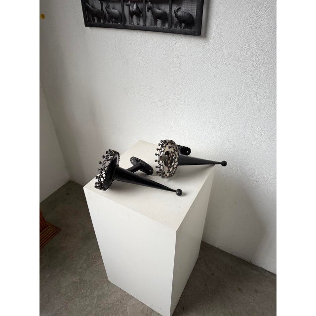 Pair of black metal wall sconces with a brutalist look. We love their conical shape ending in a very elegant round tip....