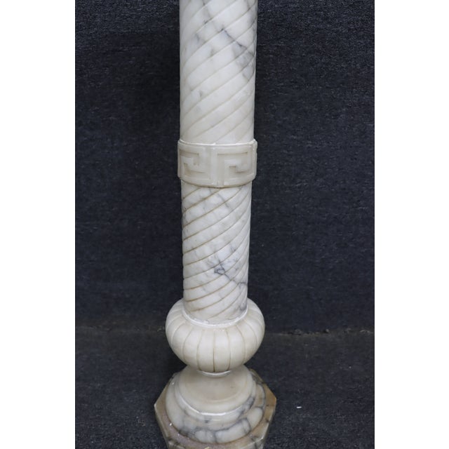 Elegant Italian carved white marble pedestal featuring a spiral twist column accented by a carved Greek key band and a...