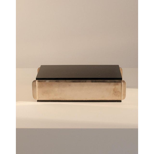 An interplay of metal and acrylic defines this sculptural italian box. The removable lid, rendered in jet-black acrylic,...