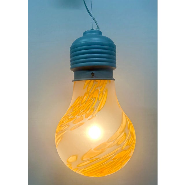 Blown glass pendant in the shape of a light bulb with single-color orange murrine hand-rolled by master glassmakers,...