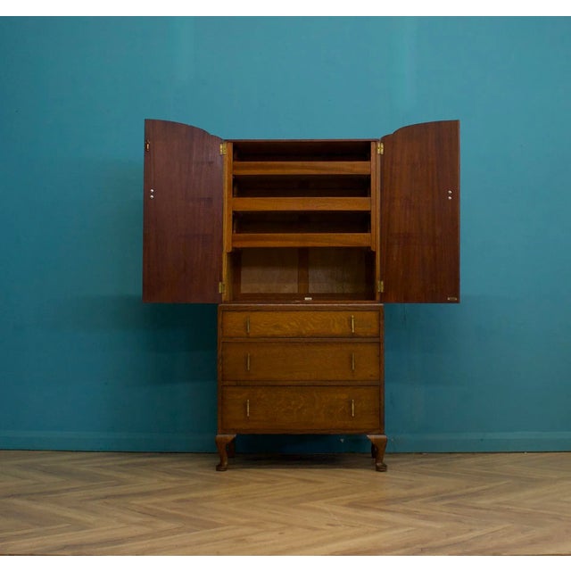An impressive quality Art Deco oak tallboy or housekeeper’s cupboard, circa 1930s Standing on Queen Anne style feet The...