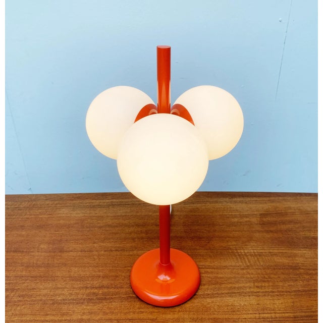Imposing Space Age table lamp from Kaiser Leuchten in a special color. The central body of the lamp is orange. The slender...