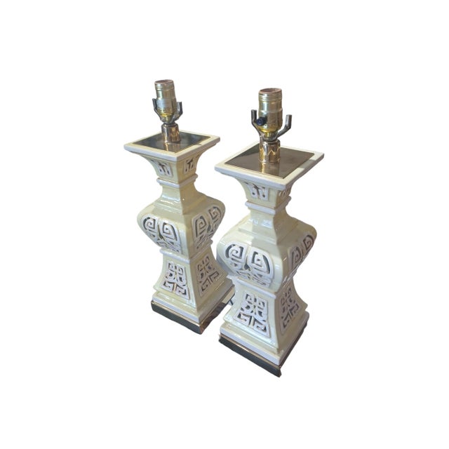 Pair of vintgae ceramic tiki style table lamps with brass accents. Lamps are pierced and in yellow amd cream colors.