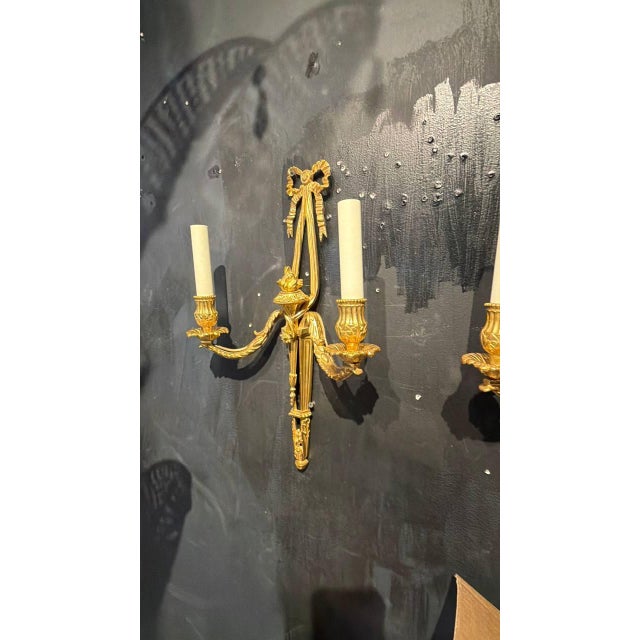 Circa 1940’s French gilt bronze sconces with ribbons and flames, in style of Luis XVI. 2 lights