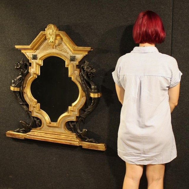 Italian mirror from the late 19th century. Carved, lacquered, and gilded wood furniture in an eclectic style with winged...