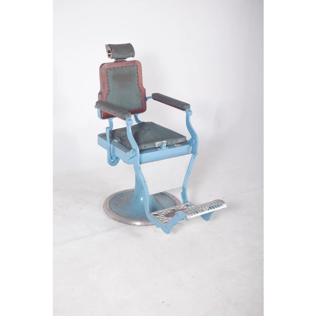 Barber chair. Made of light blue enameled metal and upholstered in dark synthetic leather with stripes. The sturdy...