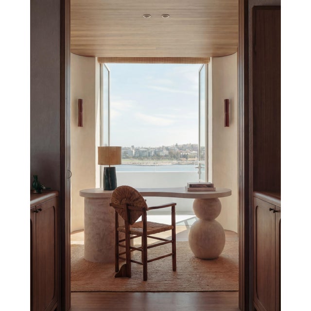 This sculptural travertine desk is defined by its organic form and architectural balance. One side is anchored by stacked...