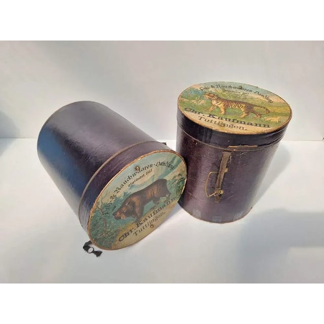 A set consisting of two rare muff boxes from the turn of the century. Beautiful lithographs on the cardboard lid.