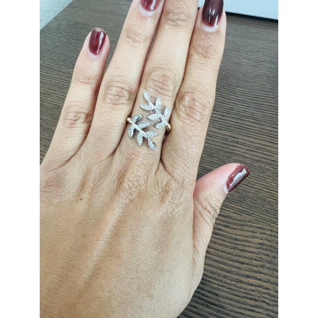 This unique ring has 0.28 carats of Natural Diamonds and has a delicate yellow gold wired shank with two white gold leaves...