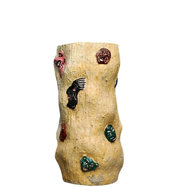 This umbrella stand is crafted from polychrome ceramic and features various relief masks typical of the work produced by...