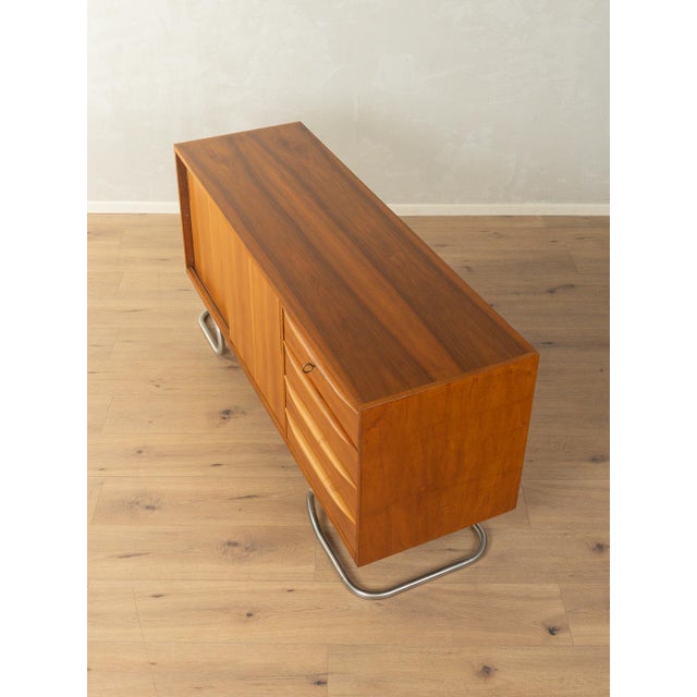 A stunning, partially solid wood sideboard in Scandinavian style from the 1950s. The body is finished in walnut veneer and...