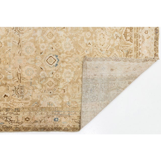 Elevate your interior with this exceptional vintage hand-knotted wool area rug, featuring a sophisticated palette of muted...