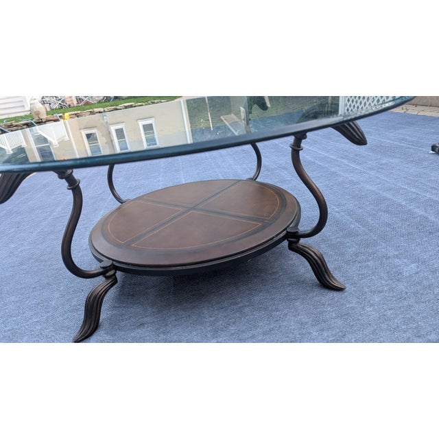 A contemporary coffee table by LaBarge, circa 1990s. Features a pencil polished glass top over a swooping iron base with...
