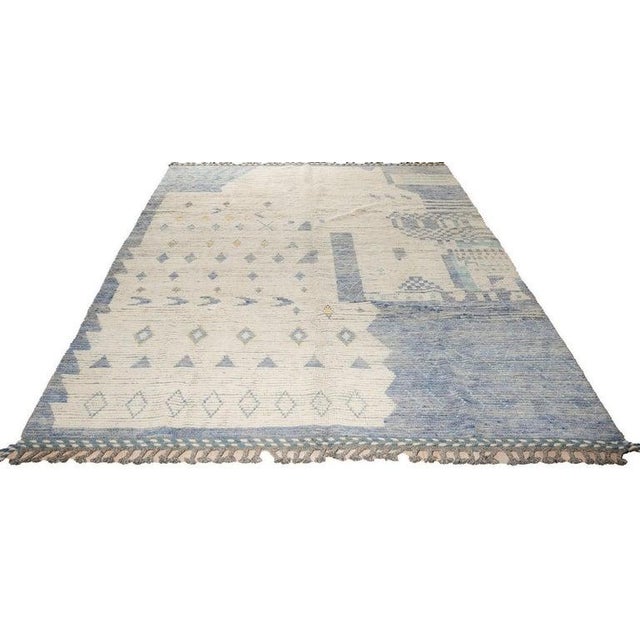 This gray wool rug is a hand knotted pile carpet designed in the style of a traditional Berber carpet. It functions as a...
