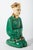 Traditionally clothed Chinese man in simple traditional green clothing with gold accents and headwear. Figure is in...