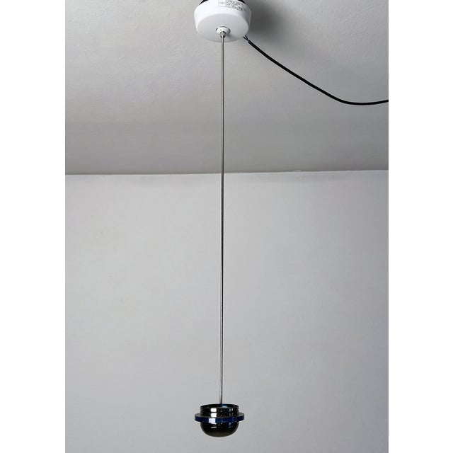 Suspension lamp with fixed stem in polished steel. The diffuser is made of metal and has a blue glass decoration edge. The...