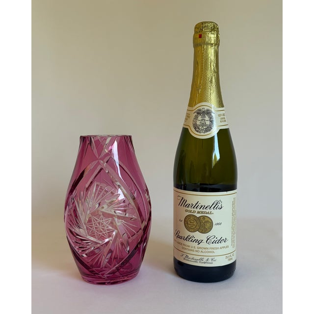 A striking cranberry-pink cased-glass vase featuring deeply cut geometric decoration that reveals the clear glass beneath....