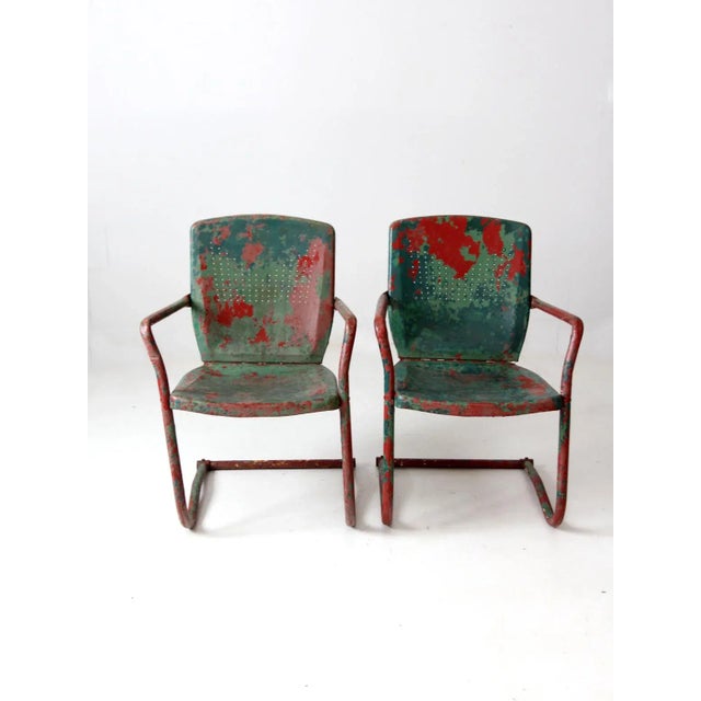 This is a pair of mid-century patio chairs. The metal garden chairs have bouncer frames with perforated metal seats and...