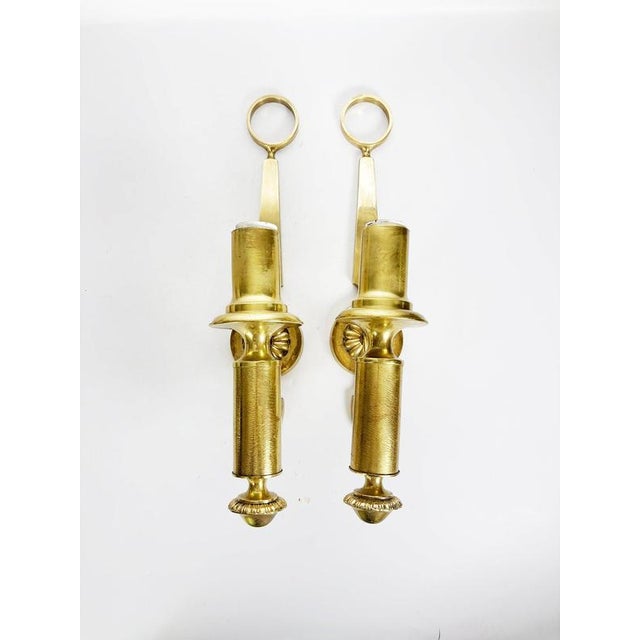 Elegant pair of neoclassical-style brass wall sconces from 1960s France, distinguished by their refined architectural...