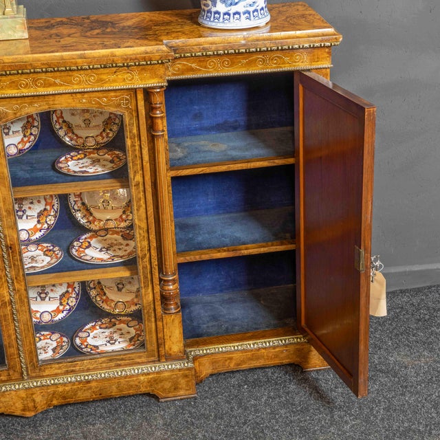 A fine burr walnut veneered mid Victorian break front credenza, the outer cupboard doors set with ormolu framed Wedgewood...