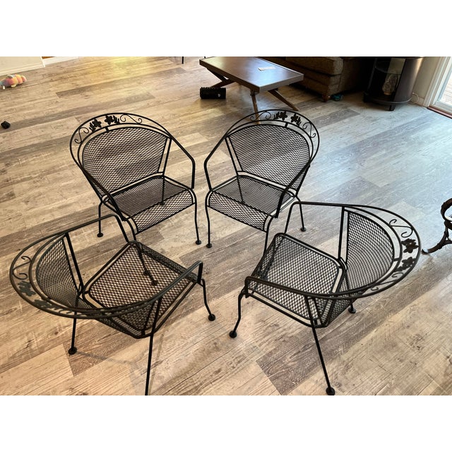 set of four vintage mid-century modern black wrought iron patio dining chairs. Featuring a highly sought-after barrel-back...