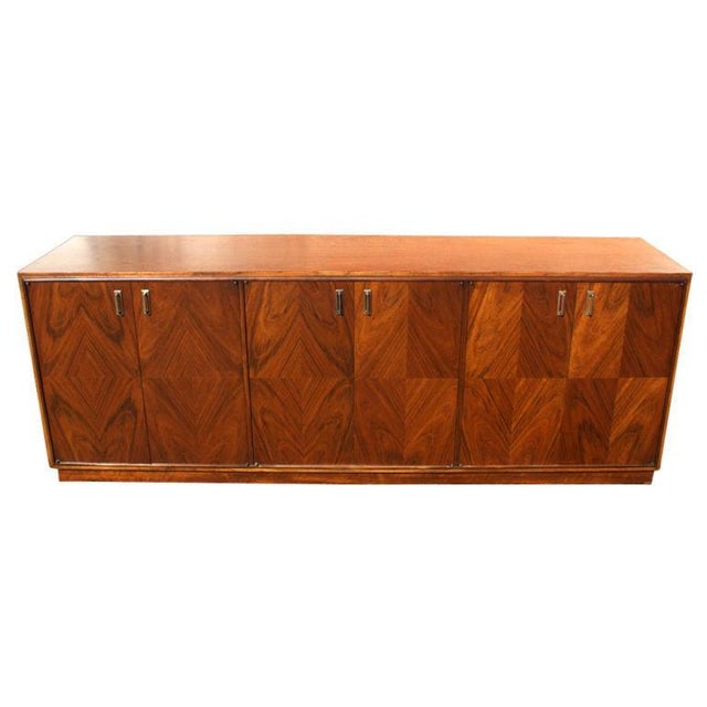 A Mid-Century Modern buffet in the manner of Renzo Rutili. A walnut case with doors faced in squares of contrasting exotic...