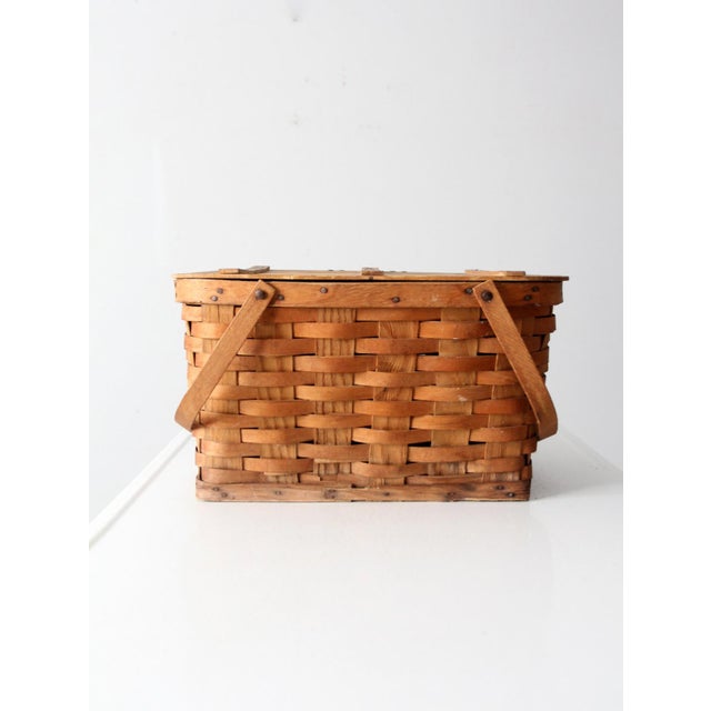 This vintage picnic basket features a traditional splint weave design and hinged bentwood handles, offering a timeless,...
