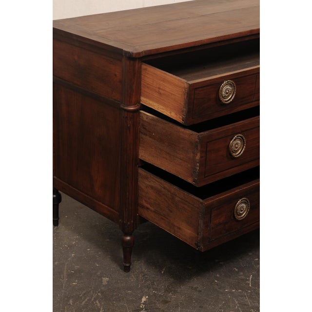 A French Louis XVI Provincial walnut commode, with beautiful hardware, from the early to mid 19th century. This antique...