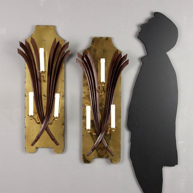 Pair of three-light wall lamps, wooden structure covered with brass sheet, wrought iron decoration and palm leaf...