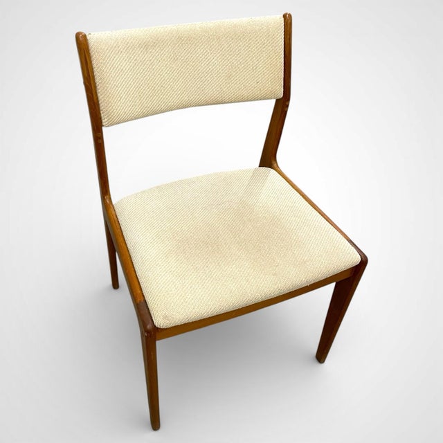 Set of four mid century Scandinavian style dining chairs in solid teak. Clean, minimalist design with tapered legs and...