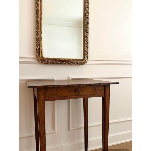 A charming 19th-century French side table featuring a beautifully understated silhouette, warm wood tones, and a lovely...