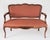 Vintage upholstered Louis XV style settee. The upholstery is a mauvish/red color. No makers mark. Some age wear/scuffs to...